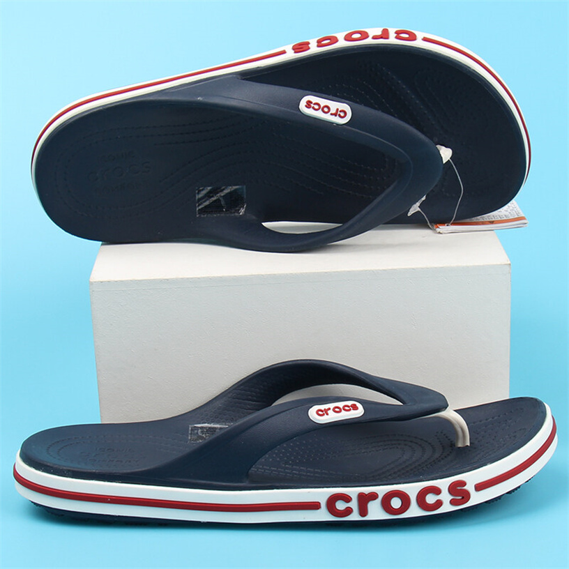 รองเท้าแตะฟลิปฟล็อป Crocs สีน้ำเงิน สวมกับกางเกงขาสั้น มุมด้านข้างโชว์ลุคลำลองทะเล
