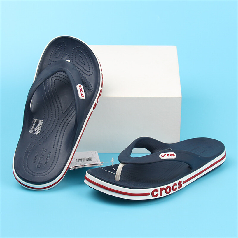 รองเท้าแตะฟลิปฟล็อป Crocs สีน้ำเงิน สวมกับกางเกงขาสั้น มุมด้านข้างโชว์ลุคลำลองทะเล