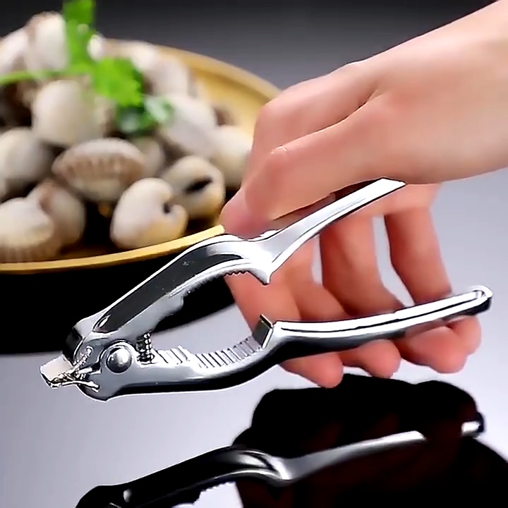 คีมแกะหอยแครงสแตนเลสสีเงิน หัวแหลมเสียบก้นหอยแครงบนจานทองคำ ใบผักชีสดใหม่ ด้ามจับโค้งมนถนัดมือ